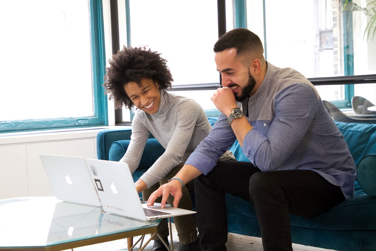2 mensen werken samen terwijl ze lachend kijken naar hun laptops.
