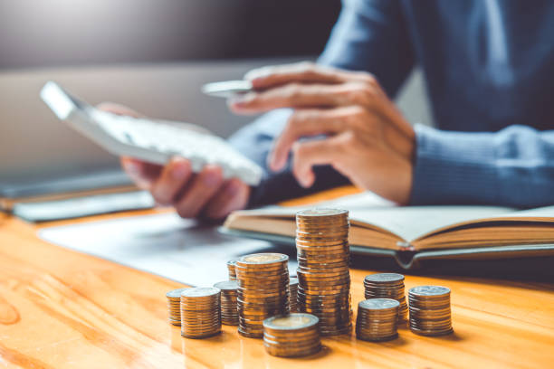 Concept voor het besparen van geld: een mannenhand die munten op een rij legt en 'Financiën' schrijft